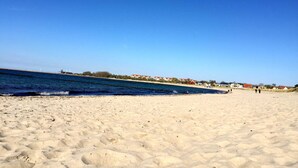 A sandy beach with a clear blue sky and calm sea.