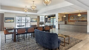Un hall d’hôtel spacieux avec une longue table à manger, des sièges confortables et un coin cuisine moderne en arrière-plan.