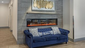 Un hall d’entrée moderne avec un canapé bleu, une cheminée et une grande œuvre d’art abstraite accrochée au mur.