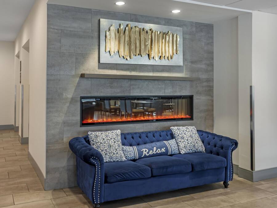 A modern lobby with a blue sofa, a fireplace, and a large abstract art piece on the wall.