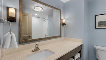 A bathroom with a large mirror, a sink, and a toilet.