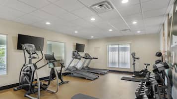 Une salle de sport équipée de tapis de course, de vélos elliptiques et de bancs de musculation.
