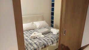 A bedroom with a bed, pillows, and neatly folded towels. - Appartamento San Massimo (Verona)
