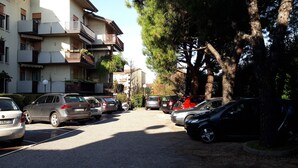 A residential street with parked cars, multi-story buildings with balconies, and trees. - Appartamento San Massimo (Verona)