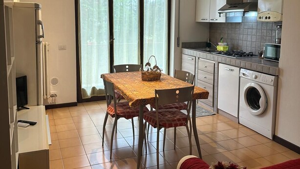 A compact living space with a dining area, kitchenette, and a washing machine. - Appartamento San Massimo (Verona)