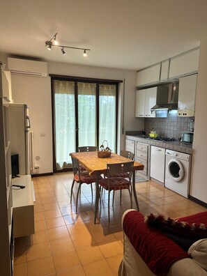 A compact living space with a dining area, kitchenette, and a washing machine. - Appartamento San Massimo (Verona)