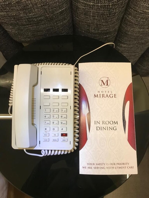 Una habitación de hotel con un teléfono y un menú para servicio a la habitación.