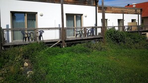A modern building with a white facade, wooden deck, and outdoor seating. - HopfenErlebnisHof (Altmannstein)