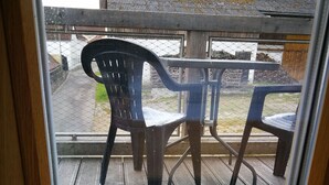 A wooden deck with a potted plant and two plastic chairs. - HopfenErlebnisHof (Altmannstein)