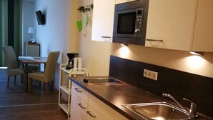 A modern kitchen with a microwave, sink, and wooden flooring. - HopfenErlebnisHof (Altmannstein)