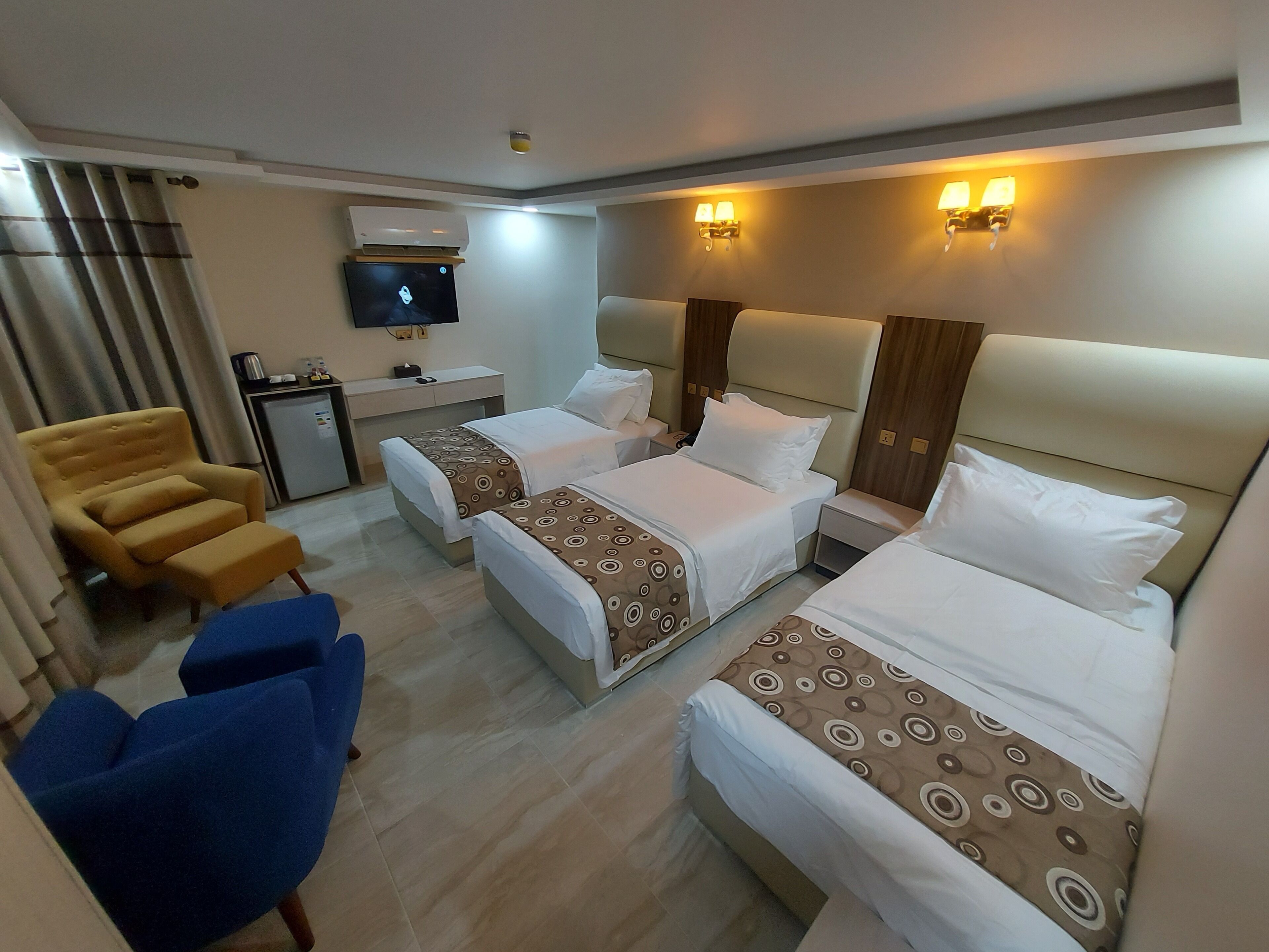 A hotel room with two beds, a desk, a chair, and a TV.