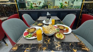 A dining area with a marble table, red and grey chairs, a fish tank, and a variety of food items. - Jordan Seasons Hotel (Aqaba)