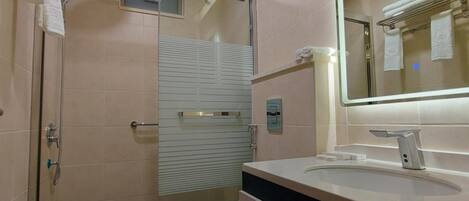 A modern bathroom with a glass-enclosed shower, a toilet, and a vanity with a mirror.