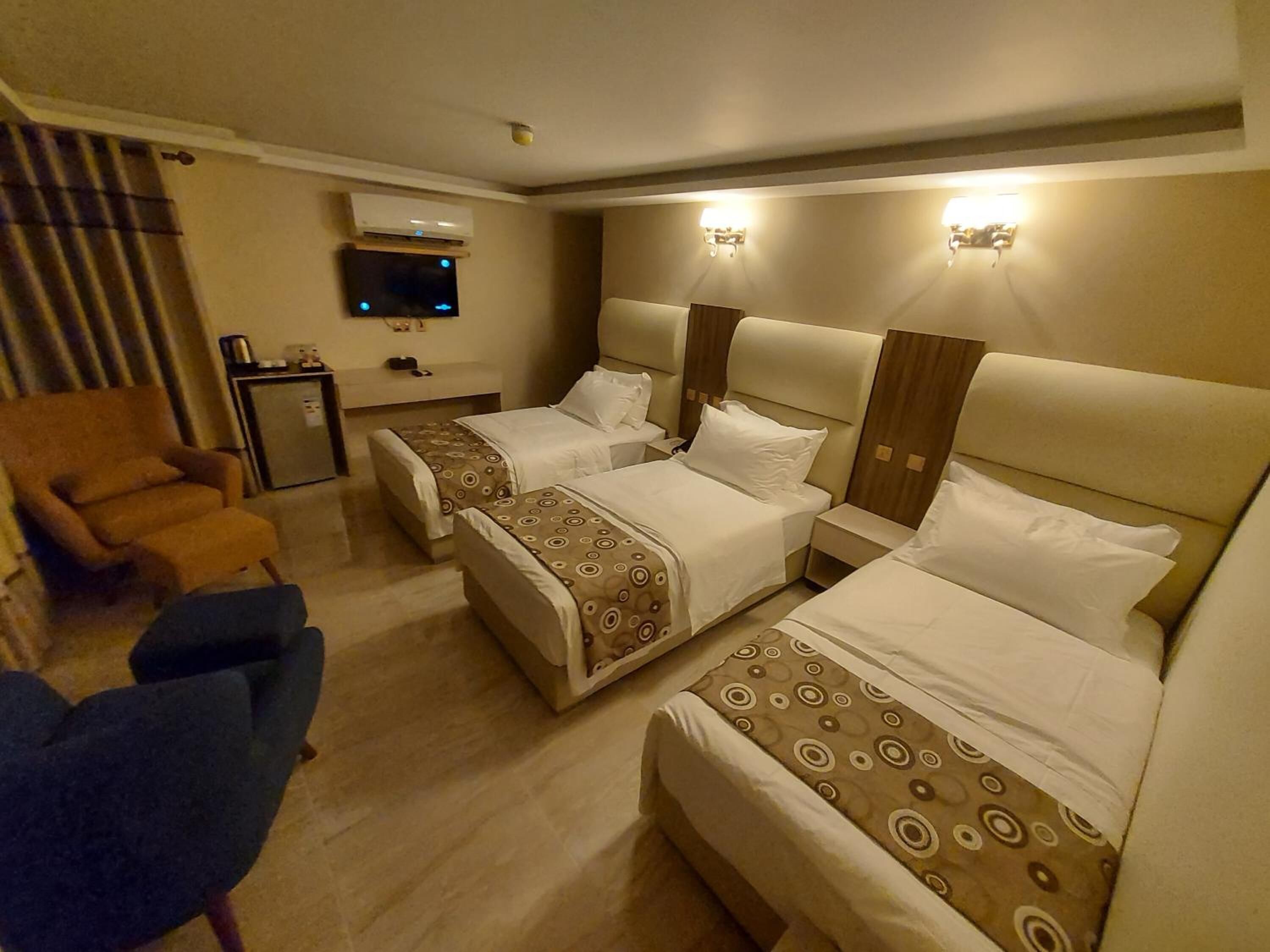 Quarto de hotel com duas camas, televisão, escrivaninha e uma cadeira.