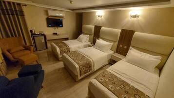 Quarto de hotel com duas camas, televisão, escrivaninha e uma cadeira.