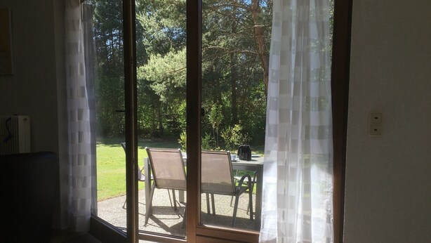 Une pièce dotée d’une porte-fenêtre coulissante donnant sur une terrasse extérieure avec une table et des chaises.