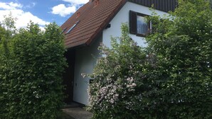 Une maison avec un toit en pente, une cheminée et une porte donnant sur une entrée abritée.
