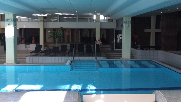 An indoor swimming pool with multiple lanes, lounge chairs, and a covered seating area with a plant. - Ferienwohnung Hüttenzauber (Sankt Englmar)