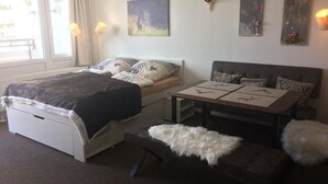 A bedroom with a bed, a sofa, a small table, and artwork on the walls. - Ferienwohnung Hüttenzauber (Sankt Englmar)