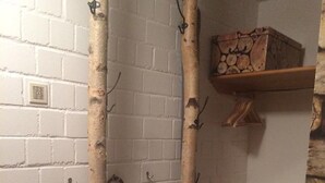 A corner of a room with a white brick wall, a wooden shelf with a box, and a small white furry stool. - Ferienwohnung Hüttenzauber (Sankt Englmar)
