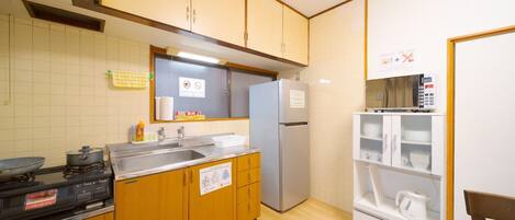 Een koelkast, een magnetron, een kookplaat, kookgerei, borden en bestek