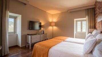 Una habitación de hotel con cama, escritorio, lámpara y televisión.