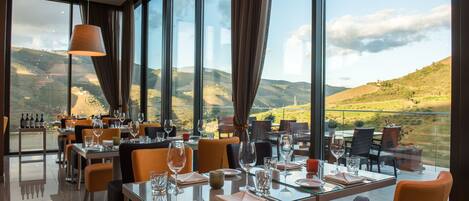 Un restaurante con mesas preparadas para comer, amplias ventanas que ofrecen vistas al campo.