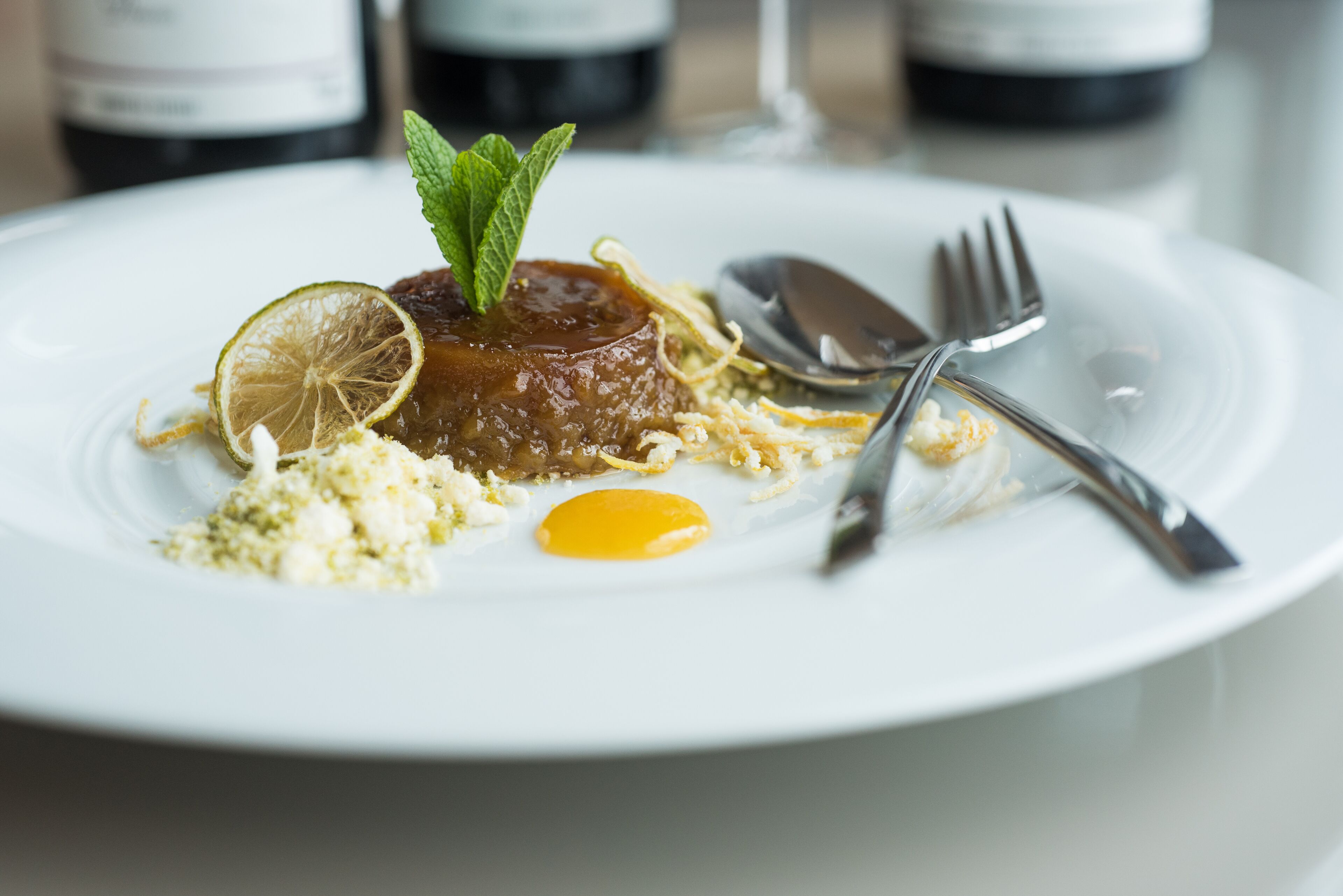 Une assiette de nourriture, garnie d’une tranche de citron, accompagnée d’une cuillère et d’une fourchette.