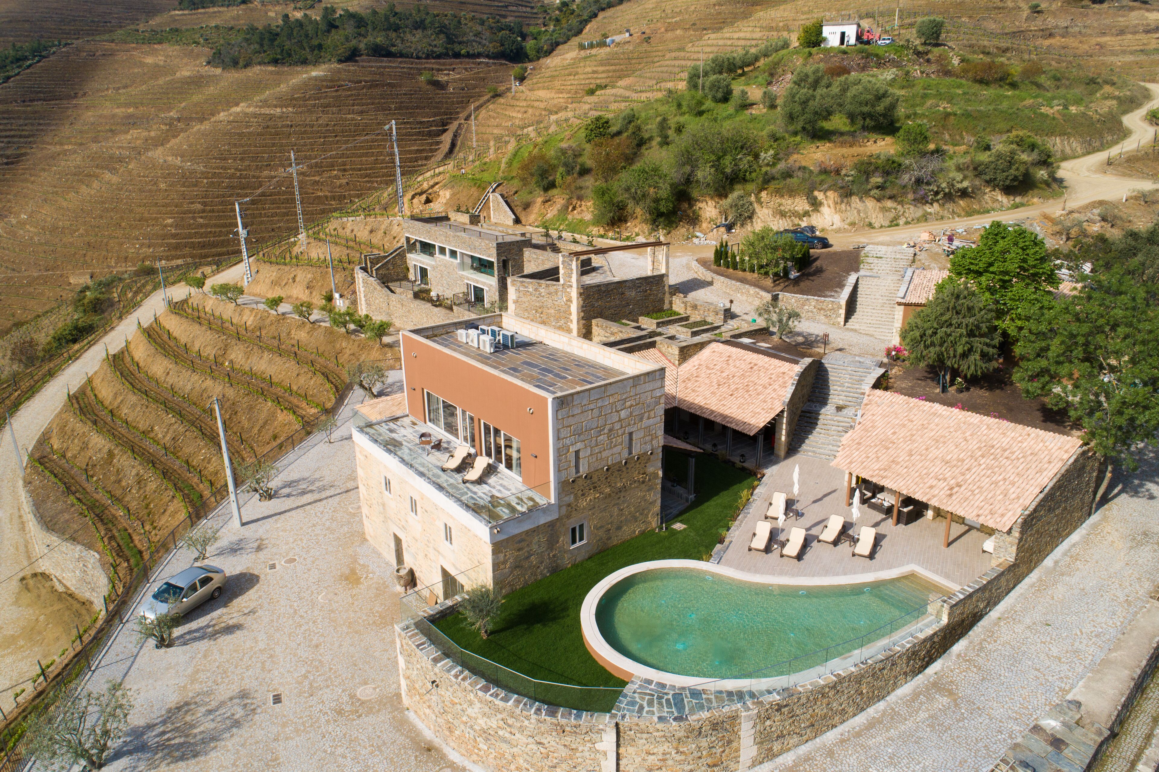 Una villa con piscina, jardín y un viñedo al fondo.