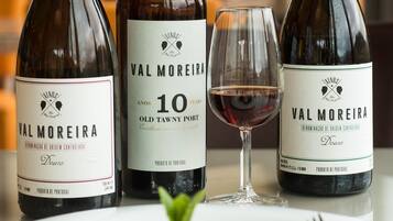 Three bottles of Val Moreira wine, a glass of red wine, and a plate of food on a table.