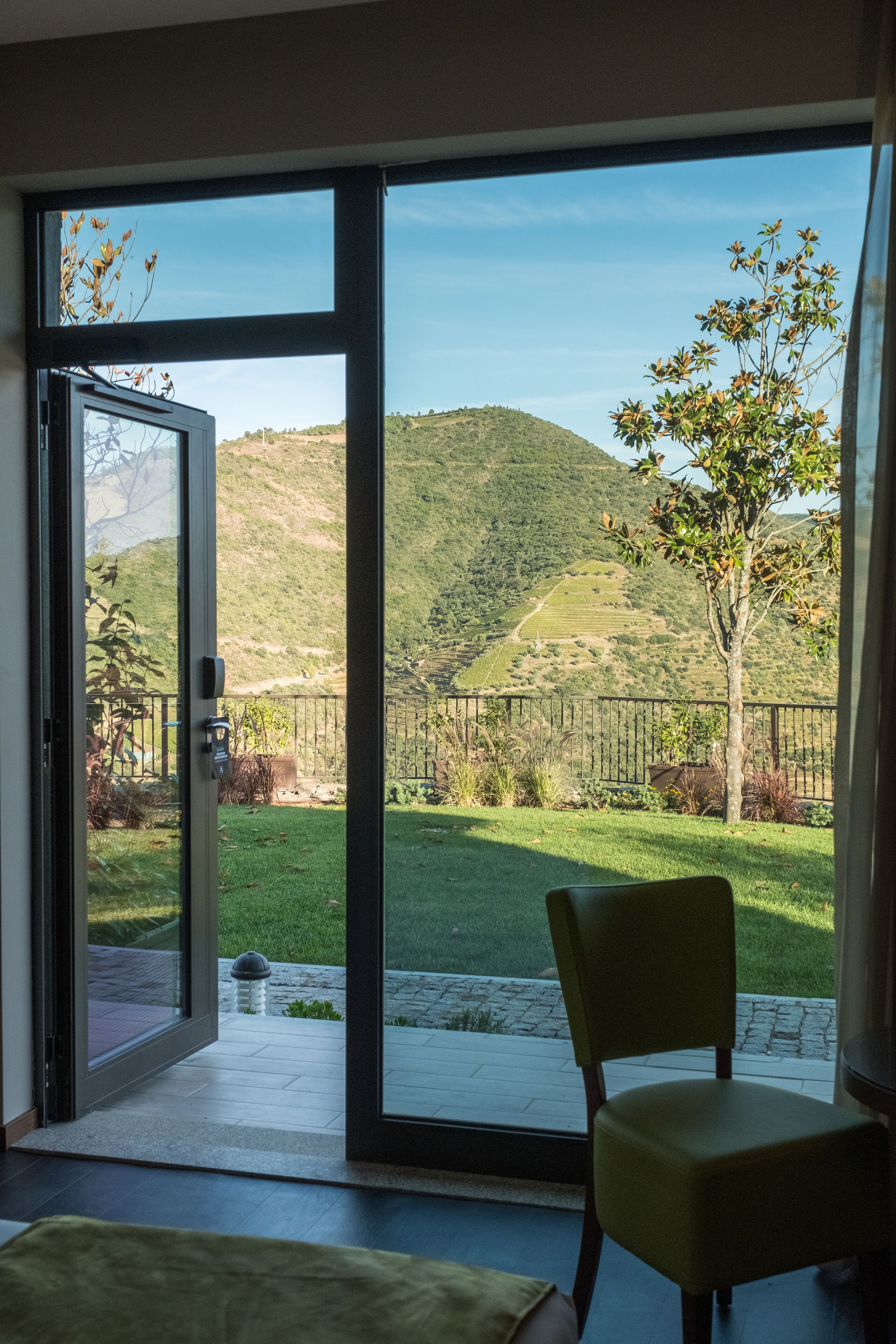 A room with a sliding glass door leading to a balcony with a view of a hilly landscape.
