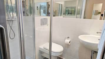 A modern bathroom with a glass-enclosed shower, a toilet, and a sink.