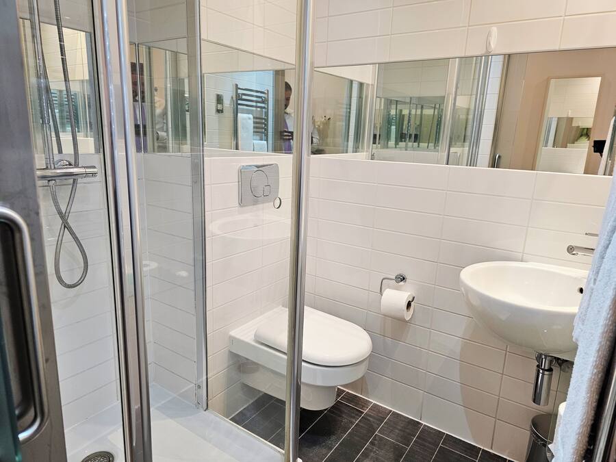 A modern bathroom with a glass-enclosed shower, a toilet, and a sink.