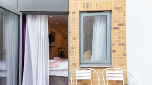 Een slaapkamer met een bed, een raam en een stoel.