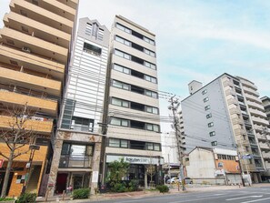 Un edificio de varios pisos con una fachada que dice 'Rakuten Stay' y un letrero de estacionamiento que indica 30 minutos de estacionamiento.
