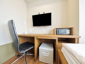 Una habitación de hotel con una cama, un escritorio con televisor, una silla y un refrigerador pequeño.