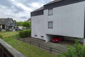 A modern building with a flat roof and a red car parked under a covered area. - Ferienwohnung Whiskey (Winterberg)