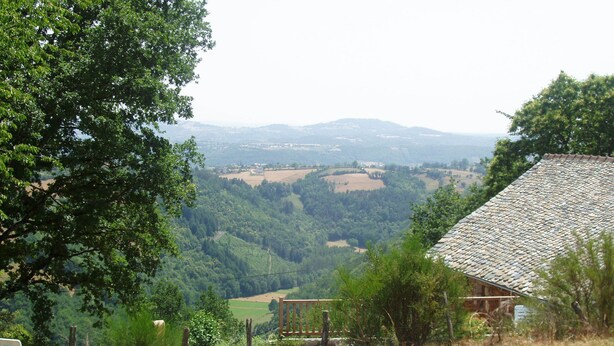 A rural landscape with a stone house, a swimming pool, and a chair. - Converted Stone Barn with Pool (Occitanie)