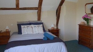 A bedroom with a bed, wooden headboard, nightstands, dresser, and a mirror. - Converted Stone Barn with Pool (Occitanie)
