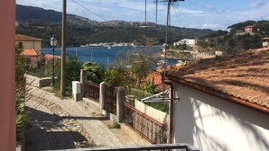 Vista costera desde un balcón con un sendero de piedra que lleva a un edificio blanco con techo de tejas.