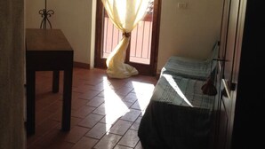 Una habitación con cama, una mesa y una ventana con cortinas.