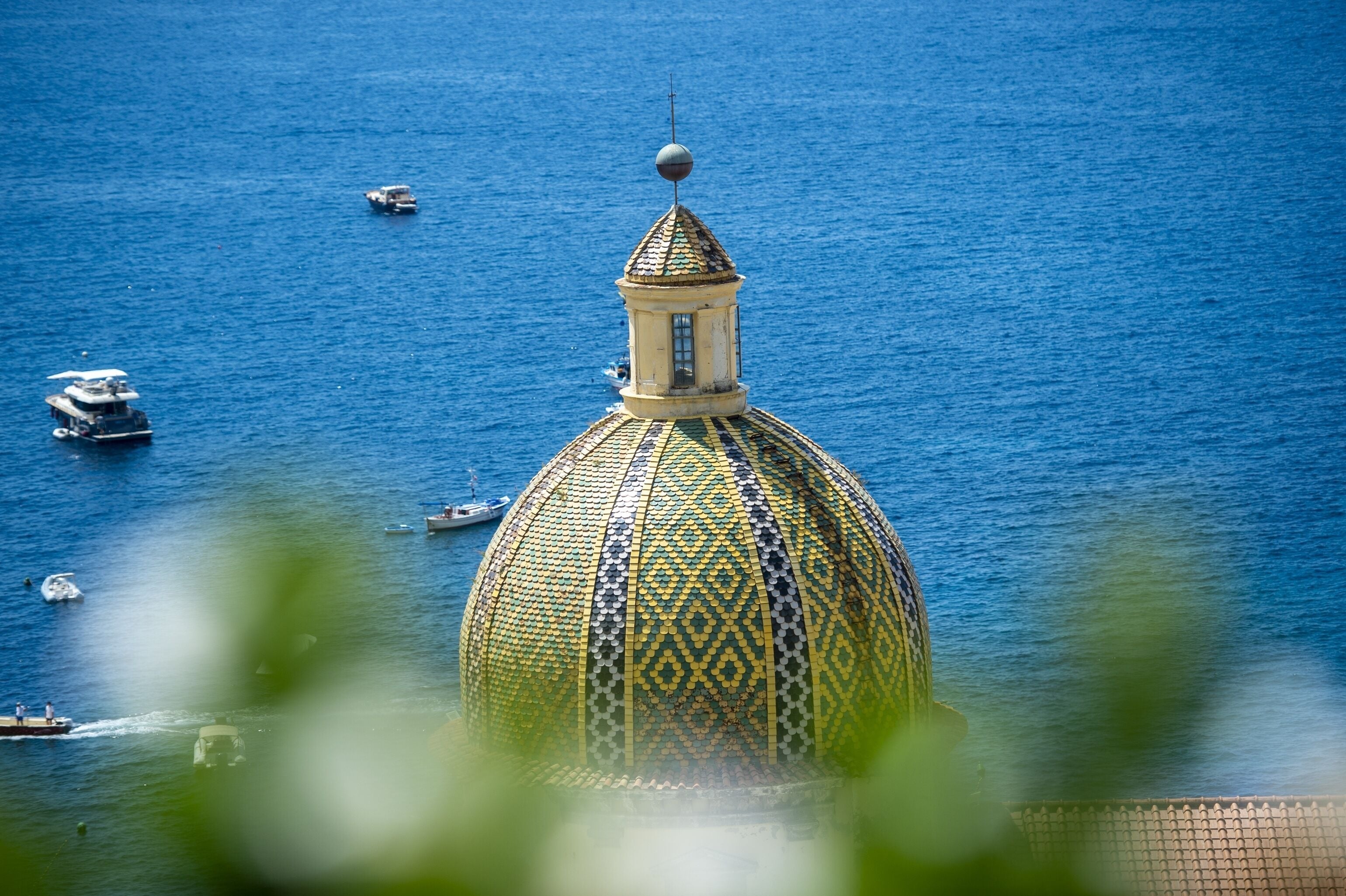 A domed building with a patterned roof, surrounded by water and boats.