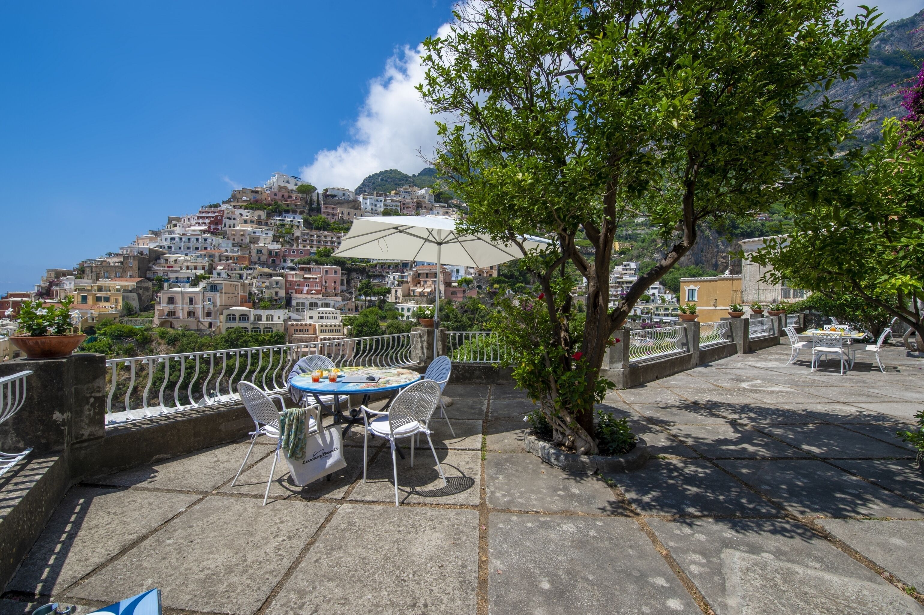 A terrace with a table and chairs, overlooking a hillside town.