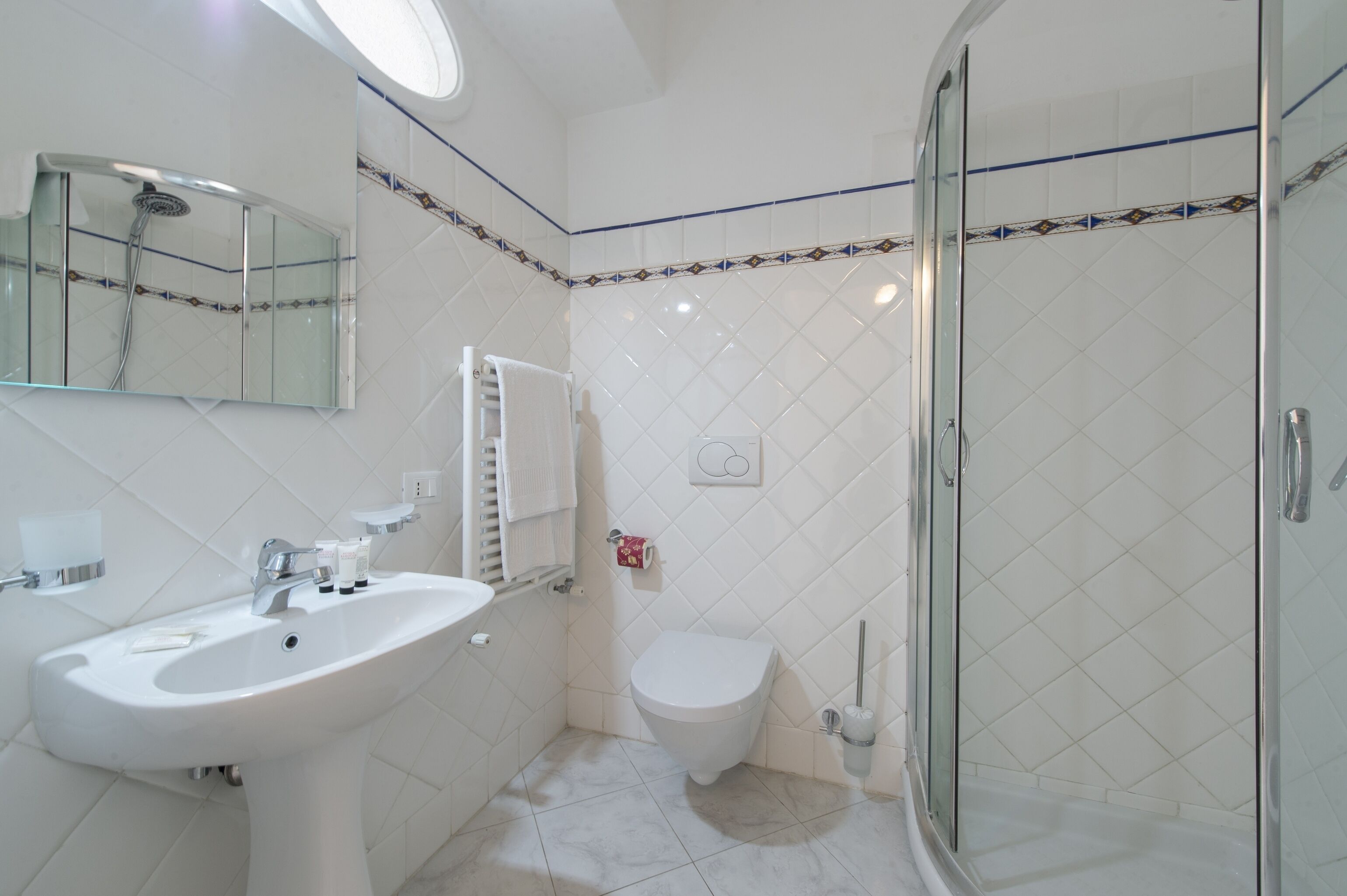 Un baño moderno con lavamanos, inodoro y ducha con mampara de vidrio.