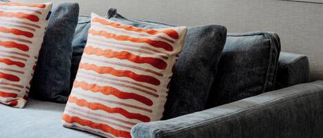 A living room with a grey sofa, two framed artworks, and patterned throw pillows.