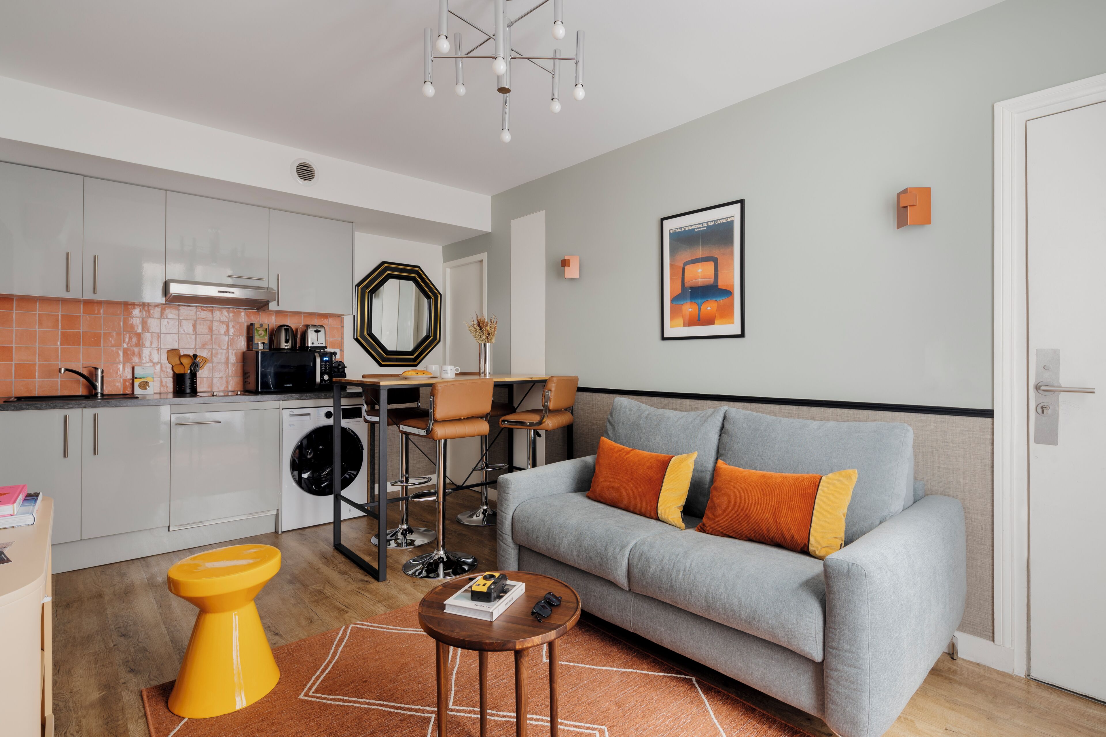 Ein modernes Wohnzimmer mit einem grauen Sofa, einem Couchtisch und einer Küche im Hintergrund.