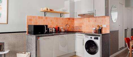 A modern kitchen with a built-in washing machine, a microwave, and a coffee maker.