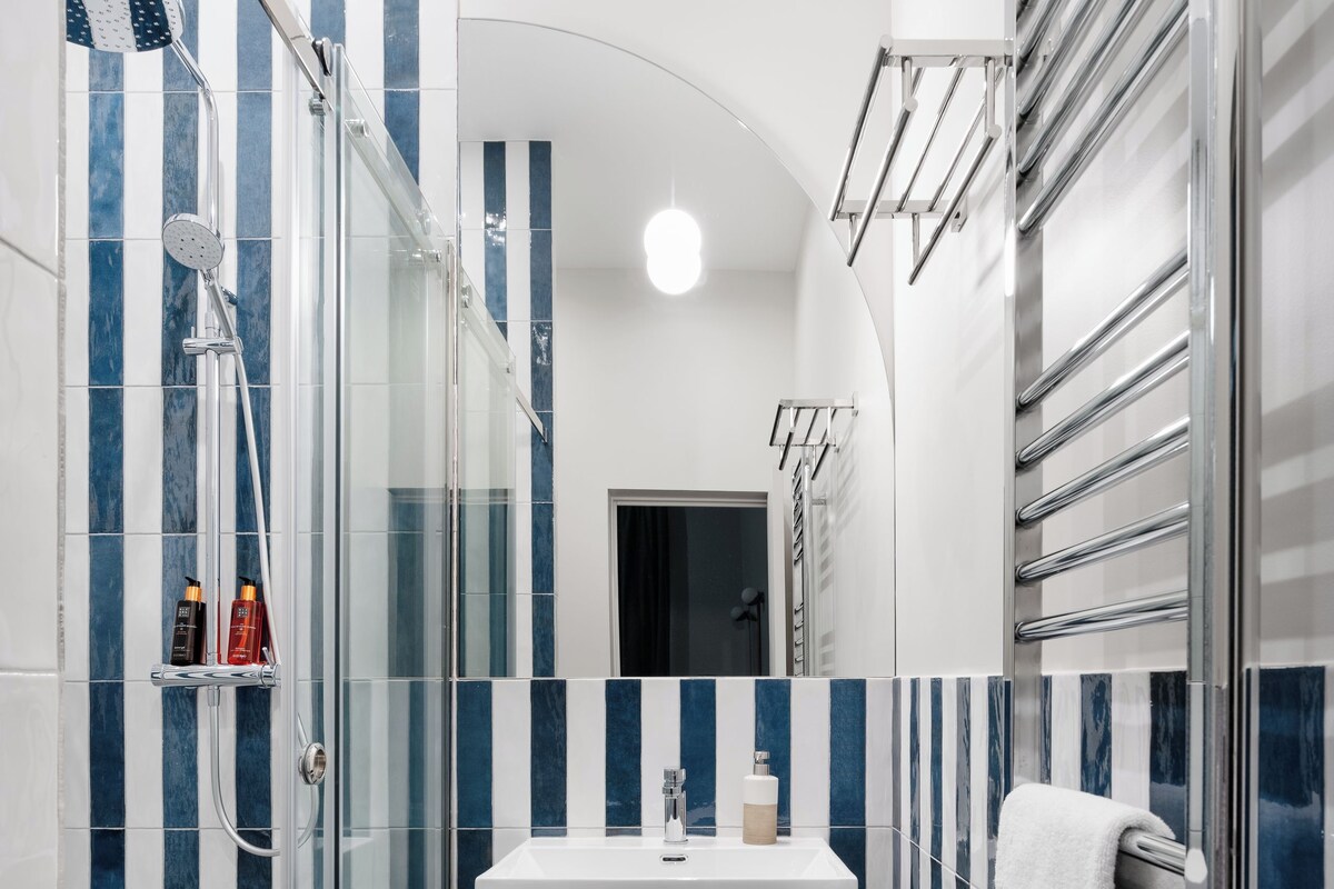 Une salle de bain moderne avec une douche à parois de verre, un lavabo blanc et un porte-serviettes.