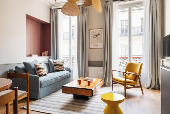 A modern living room with a sofa, armchairs, a coffee table, and a TV.
