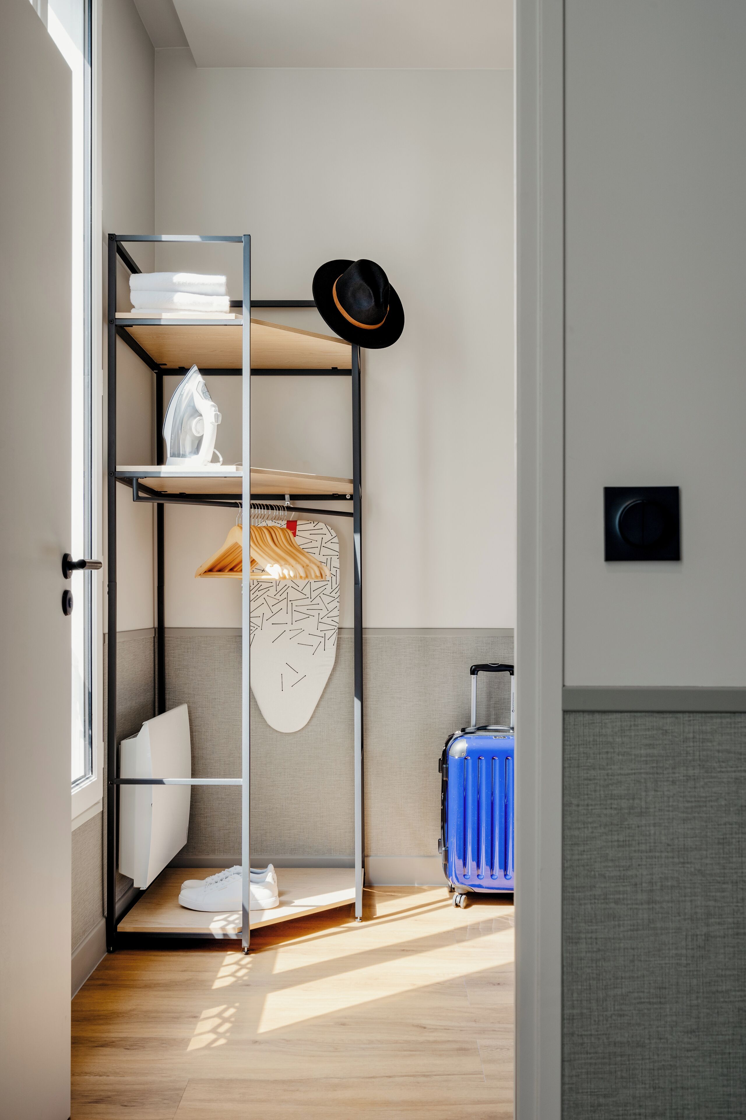 Une petite pièce avec un lit superposé, une valise et un chapeau accroché au mur.